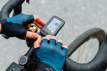 Cyclist's hands use a computer for a bicycle, close-up photo. Gadgets for cycling.