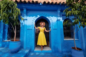 Keuken spatwand met foto Colorful traveling by Morocco. Young woman in yellow dress walking in  medina of  blue city Chefchaouen. © luengo_ua