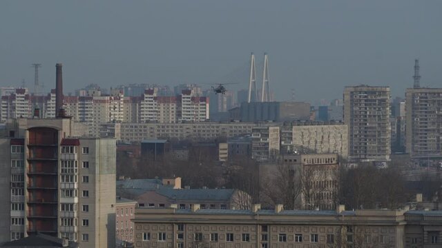 Helicopter descends takes off in the city. Helicopter with bucket suspension. Town residential areas. Helicopter over houses