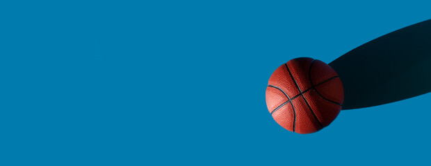 Brown new basketball ball with natural lighting on blue background. Sport team concept. Horizontal...