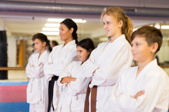 Group photo of kids and trainer in karate uniform standing in gym.