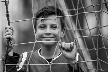 A teen boy near a goal on the soccer field. Black and white photo.