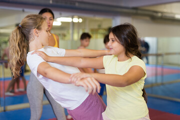 Pair of teenager school girls practicing new self-defense moves during training in gym