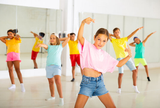 Portrait of modern tween girl krump dancer in choreographic studio with dancing children in background.