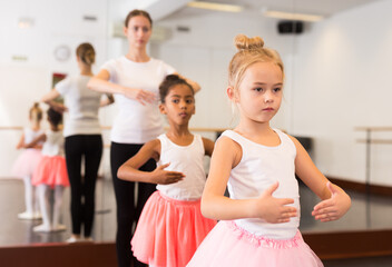Two little girls practicing choreographic elements in ballet hall