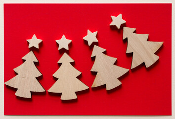 Fototapeta na wymiar wooden christmas trees and stars on red paper