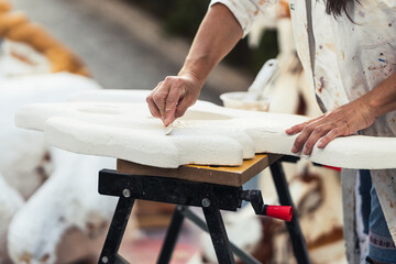 Woman in gown sticking cream on a polystyrene figure in a workshop