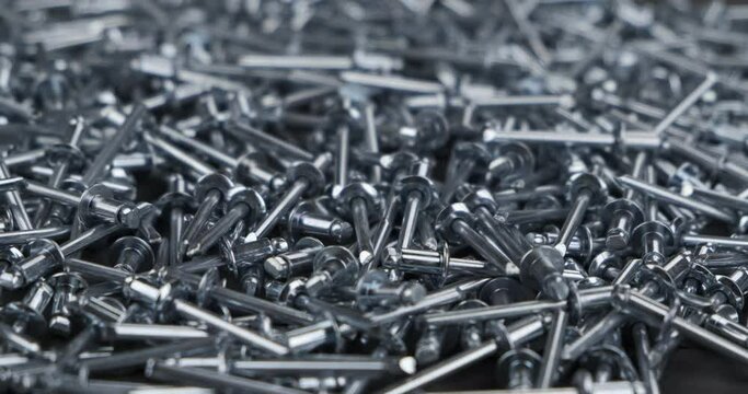 Rotating a heap of aluminum rivets. Close-up.