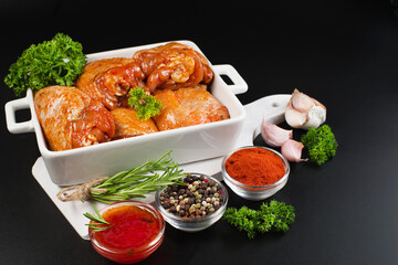 Raw chicken meat.Chicken thighs marinated in red sauce in a roasting dish with rosemary leaves and various spices.