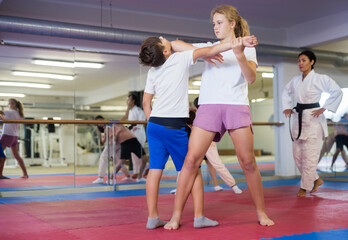 Preteen children working in pair mastering new self-defense moves at gym