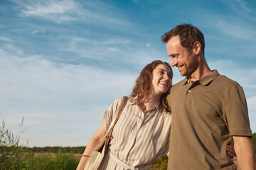 Waist up portrait of happy couple in nature against blue sky, copy space