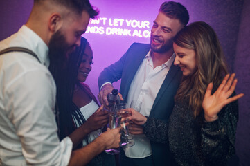 Friends dancing on a party in a club while drinking champagne