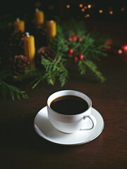 Obraz na płótnie Canvas Cup of black coffee on a wooden table. Christmas wreath in background. Copy space