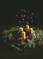 Hand crafted rustic Christmas wreath with beeswax candles, cones and evergreen sprigs . Copy space - obrazy, fototapety, plakaty