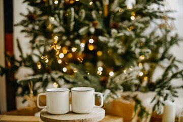 New year 2022, christmas. House room decorated for the holidays. Two cups of tea or coffee on the background of the Christmas tree. Christmas drinks. Warmth and comfort