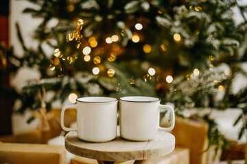 New year 2022, christmas. House room decorated for the holidays. Two cups of tea or coffee on the background of the Christmas tree. Christmas drinks. Warmth and comfort
