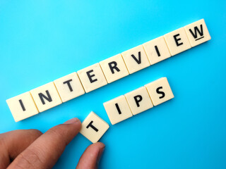 Hand holding toys word with text INTERVIEW TIPS on blue background.