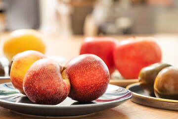 Plate with ripe red apples and other dishes with all kinds of seasonal fruits