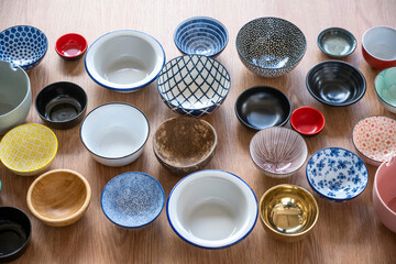 Set of empty bowls of different textures and colors on oak background