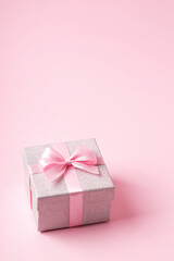 Silver glitter gift box with pink ribbon bow on pink background. Christmas, Valentine's day or birthday concept. Place for text. View from above.