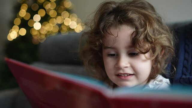 father reading a Christmas story to his little daughter enjoying as a family. Grandfather playing with his granddaughter at Christmas time and holidays