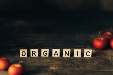 Obraz na płótnie Canvas Dark wooden background with wooden letters and farmers apples. Organic food concept.