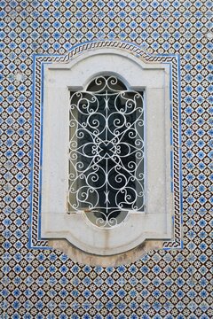 janela de ferro forjado trabalhada rodeada de azulejos portugueses.