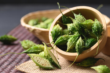 Fresh Organic bitter gourd or bitter melon in a wooden bowl, Food ingredients and herbal medicine