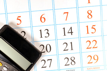Planning monthly budget and expenses. Black calculator is on the paper calendar. 