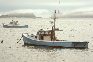 Tranquil scene in coastal Maine. Two lobster boats anchored in Owls Head harbor with ocean fog...