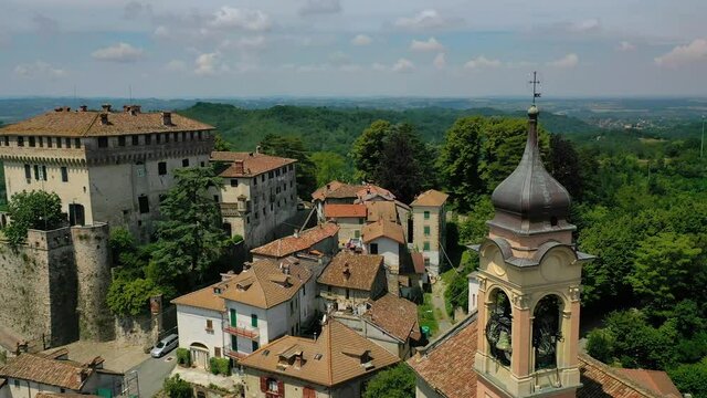 Aerial view around a bell tower and the Castello di Montaldeo, in Piedmont, Italy - circling, drone shot
