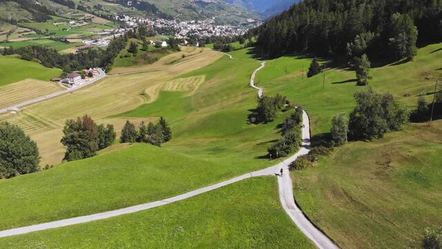 Aerial: swiss valley and mountain biker following a path