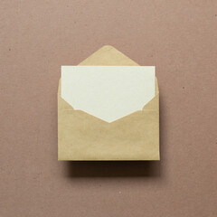 Blank card in kraft envelope on brown background. top view, copy space