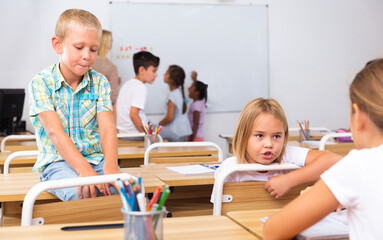 Positive primary school students are talking about homework at the desk