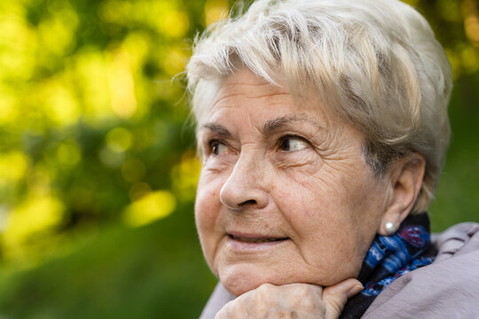 Portrait of senior blonde woman with hand on chin and hope look. Smiling elder lady thinking looking sideways. Wrinkles, skin care, copy space concepts