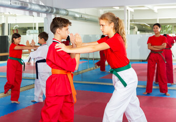 Young children sparring in pairs to practice new moves in karate class