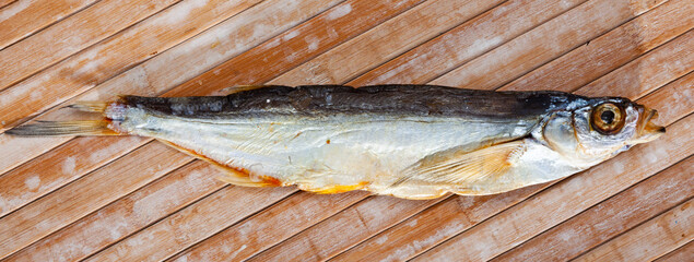 One dried salted sabrefish on light wooden background