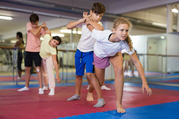 Kids exercising self-protection moves during group training in gym.