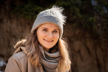 Autumn portrait of caucasian blond young smiling woman in grey sweater and beanie hat outdoor