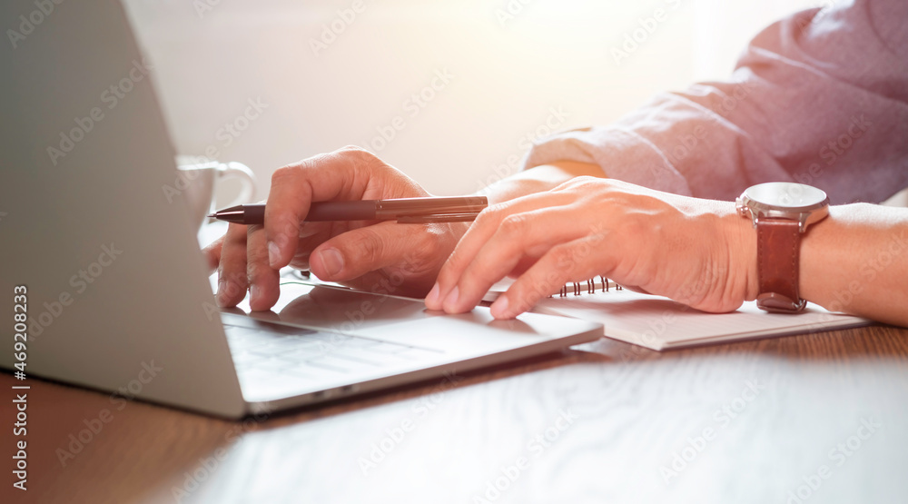 Poster close-up of man hands using and typing keyboard of laptop computer on office desk. workspace, busine