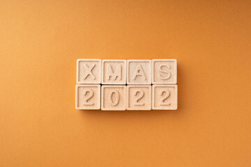 The wooden cubes say Xmas 2022. Wooden cubes with letters and numbers on an orange background. New Year's card