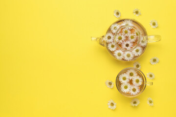 A large glass teapot and a bowl with floral tea on a yellow background. Medicinal tea.