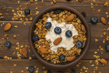Yogurt, muesli, nuts and blueberries in a bowl on the table. Flat lay.