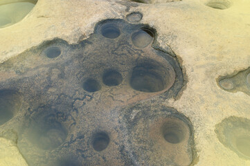 Obraz premium Background image of rocks eroded by river water, grooves and holes. Light fare.
