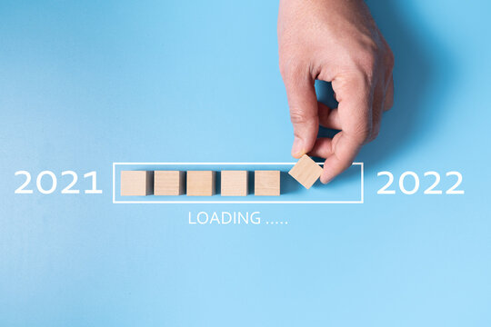 Loading new year 2022 with hand putting wood cube in progress bar