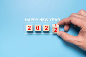 Happy new year 2022, hand flip wooden cube with the number 2021 to 2022 on blue background