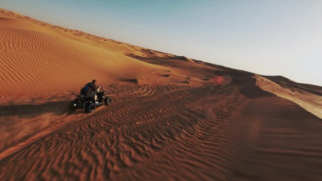FPV shot following a ATV in the Dubai Desert, during golden hour - POV aerial view