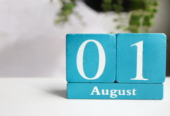 Cube wooden calendar showing date on 1 August. Wooden calendar with date on the table. blur objects...
