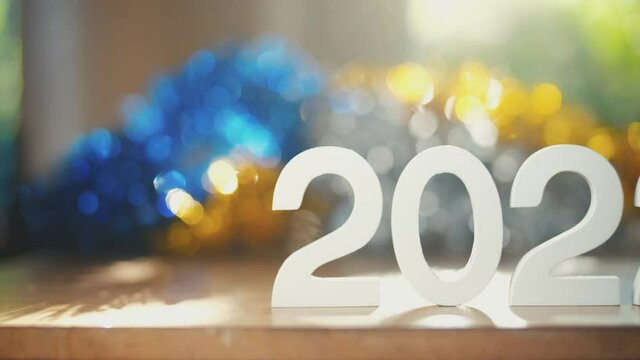 White number 2022 new year text on wooden table with colorful boken blurred  background and natural light in morning, camera slider shots