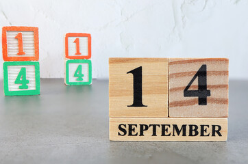 Obraz premium September 14th. Hello September, Cube wooden calendar showing date on 14 September, Wooden calendar with blur objects on background.